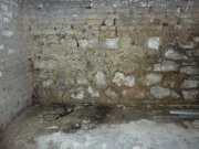 Feuchte steinerne Kellerwand mit rauem Mauerwerk und Staub auf dem Boden