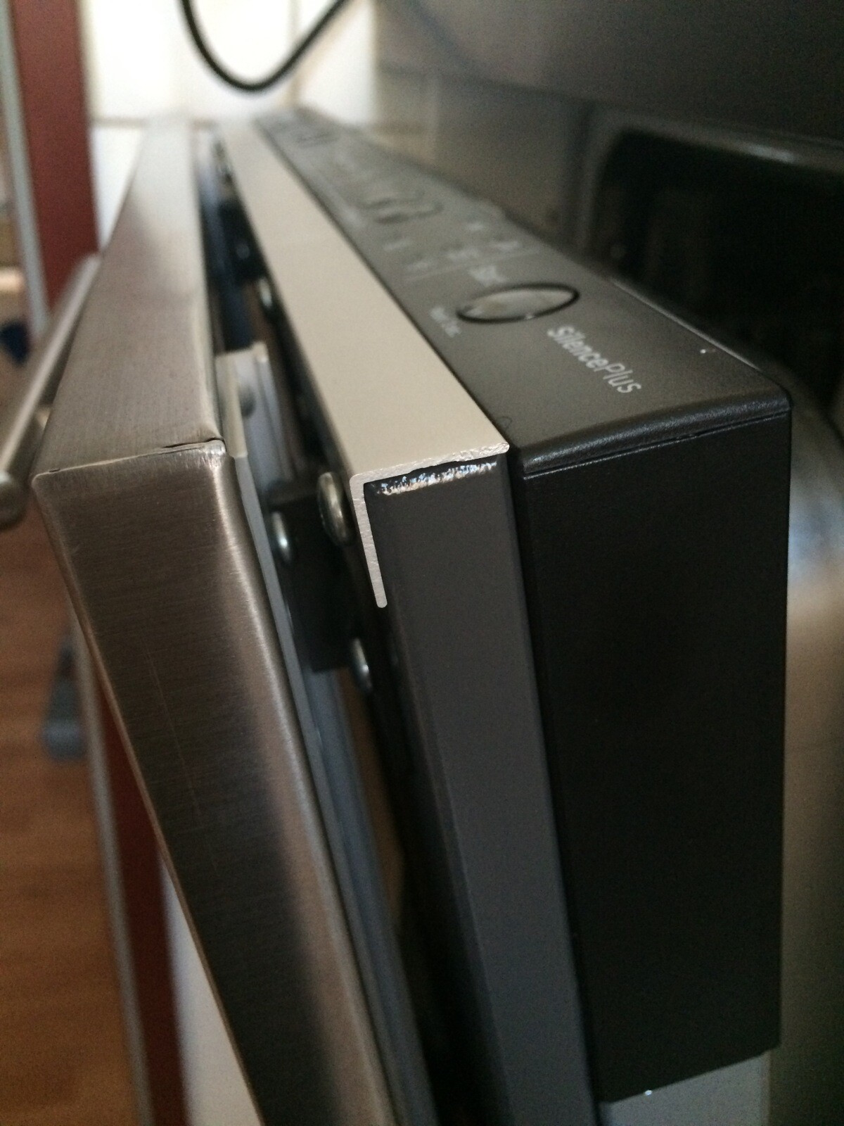 Nahaufnahme eines Küchengeräts: schwarzes Gehäuse neben silbernem Rahmen, Ecke leicht abgenutzt.