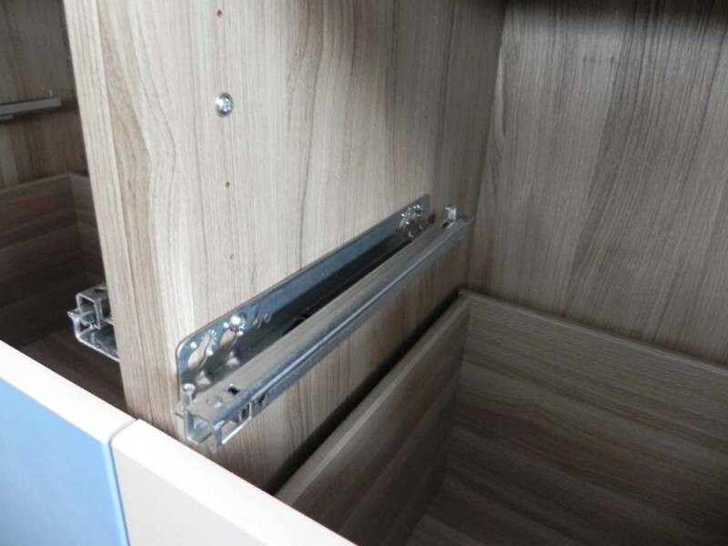 Metall-Schubladenauszug in offenem Holzschrank mit Führungsschienen.