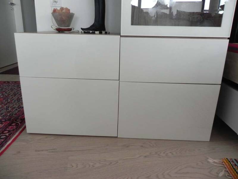 Weiße Sideboard mit vier Schubladen; Obstschale links, Schuh oben, Glasfront rechts.