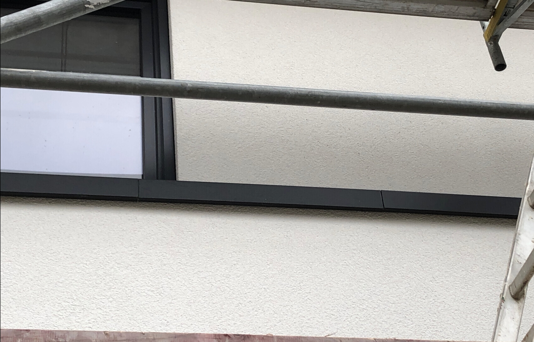 Außenwand mit Fenster und Baugerüst davor.
