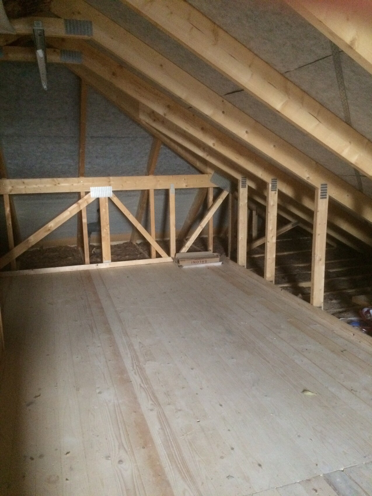 Dachboden mit sichtbaren Holzbalken, Sparren und rohem Holzfußboden