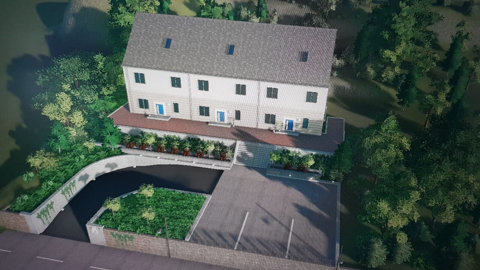 Luftaufnahme einer Reihenhausanlage mit weißen Fassaden, blauen Türen, Gartenflächen und Parkplatz.