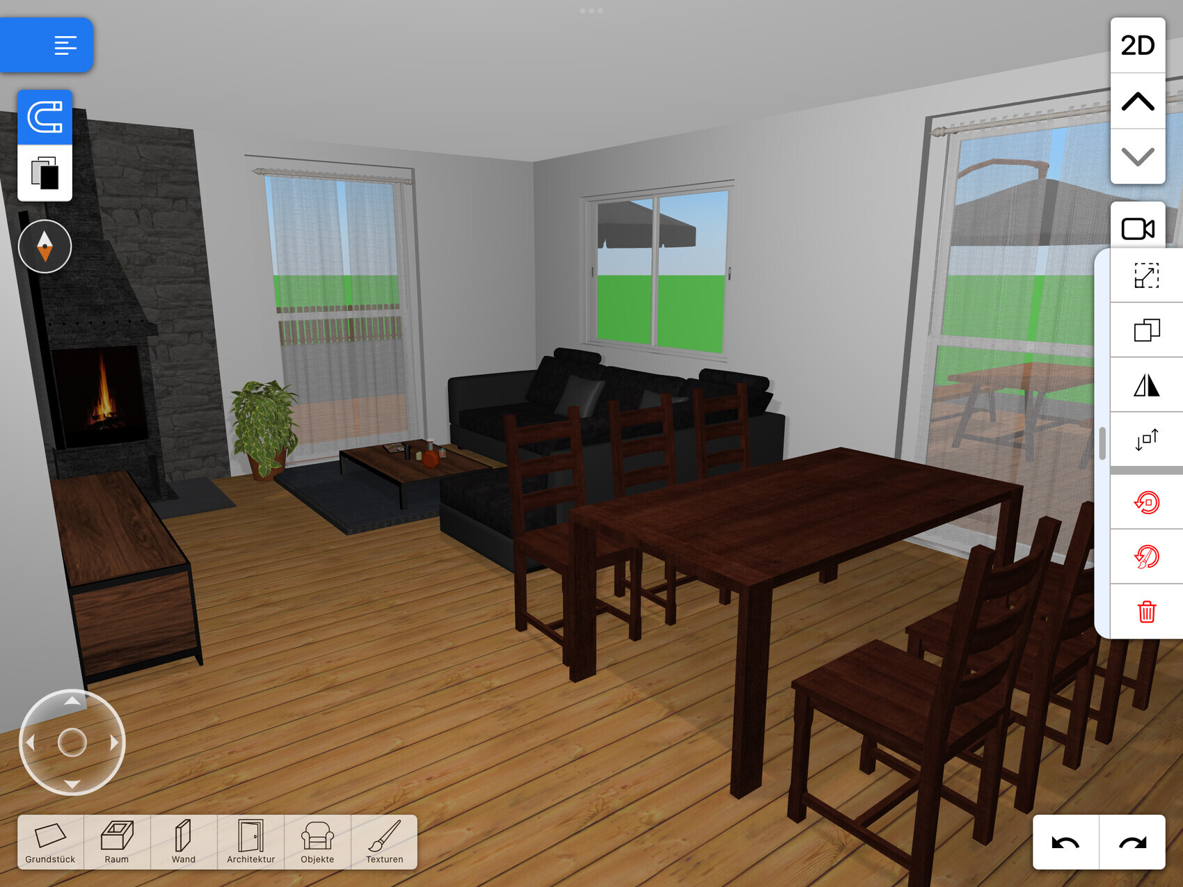 Wohnzimmer mit Kamin, Sofa-Gruppe, Esstisch und Stühle; große Fenster und Holzboden.