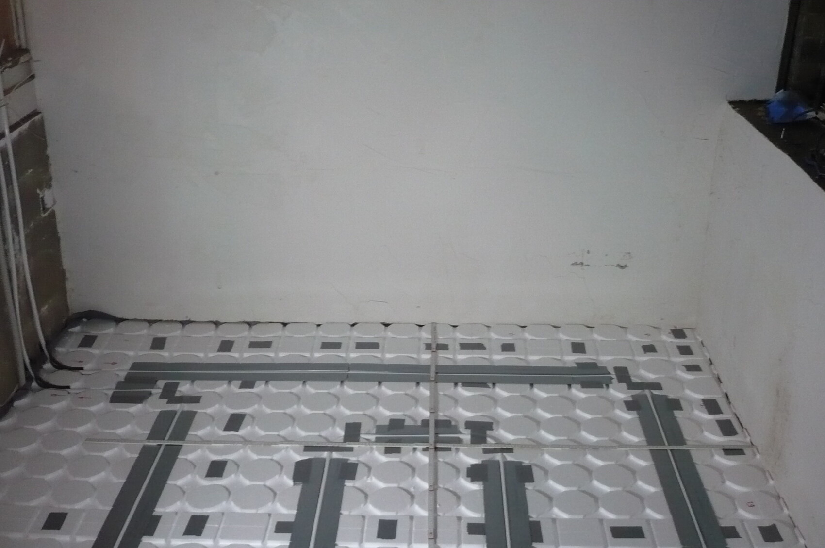 Unterbodenheizung: Heizrohre liegen auf Kunststoffplatten auf dem Bauboden eines Zimmers.