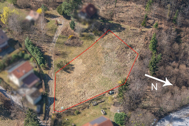 Luftaufnahme eines unbebauten Grundstücks mit roter Umrandung; umliegende Häuser und Bäume, Norden.