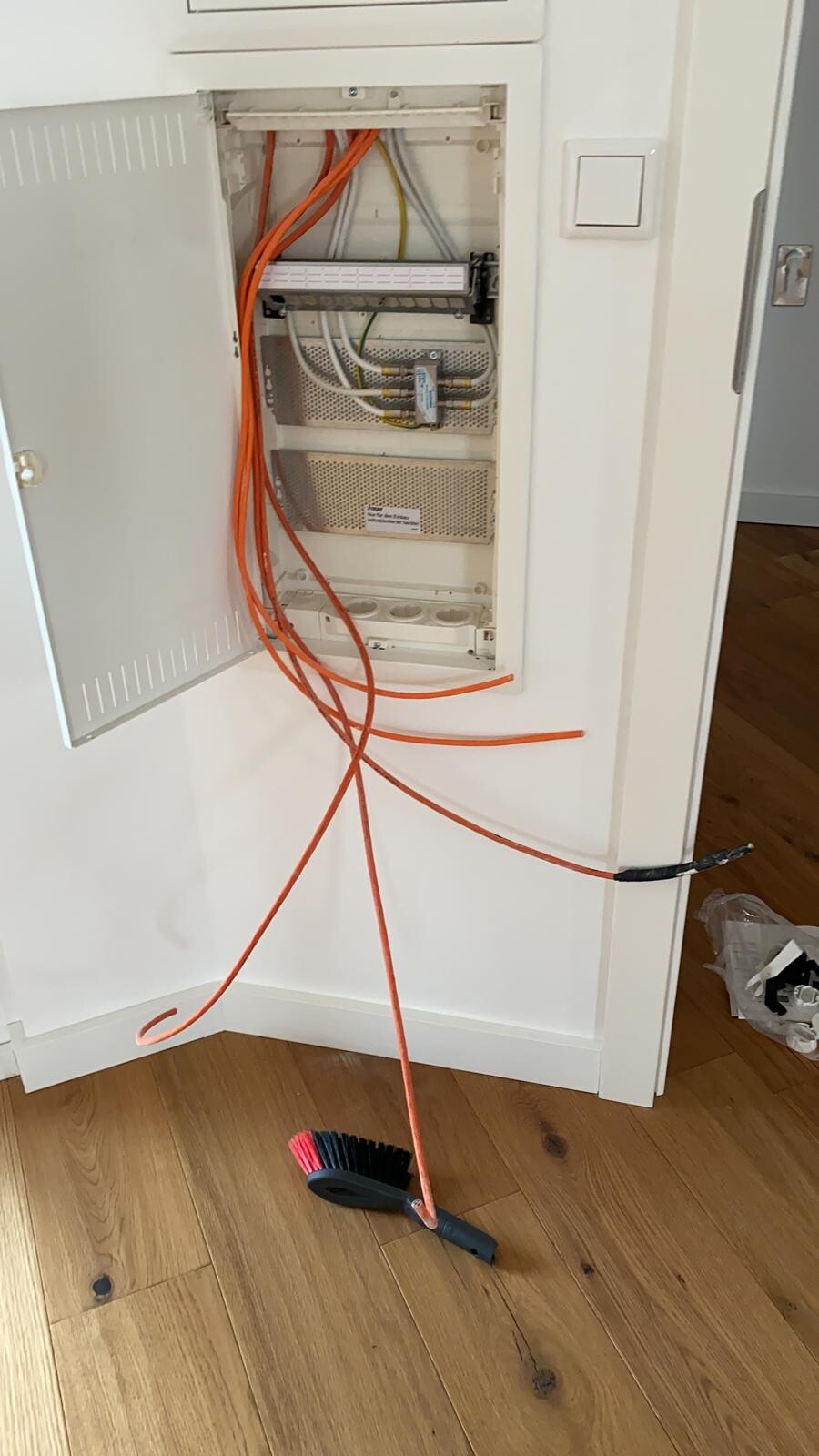 Elektrischer Verteilerkasten mit orangefarbenen Kabeln in Innenwandmontage