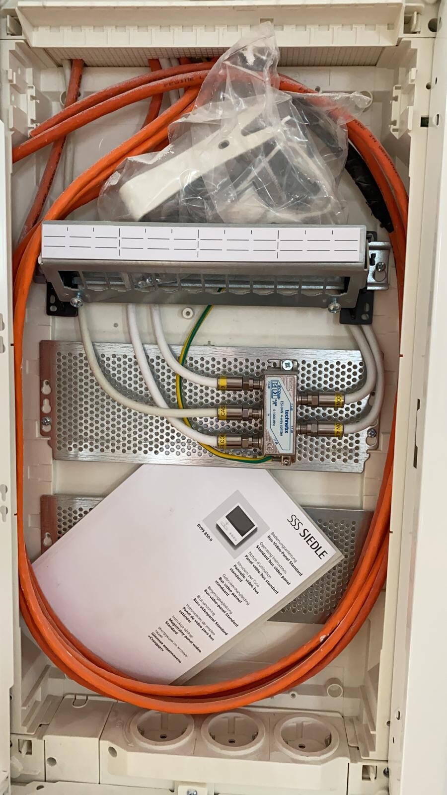 Offener Elektroverteilerkasten mit orange Kabeln und Verteilereinheit in einem Schrank