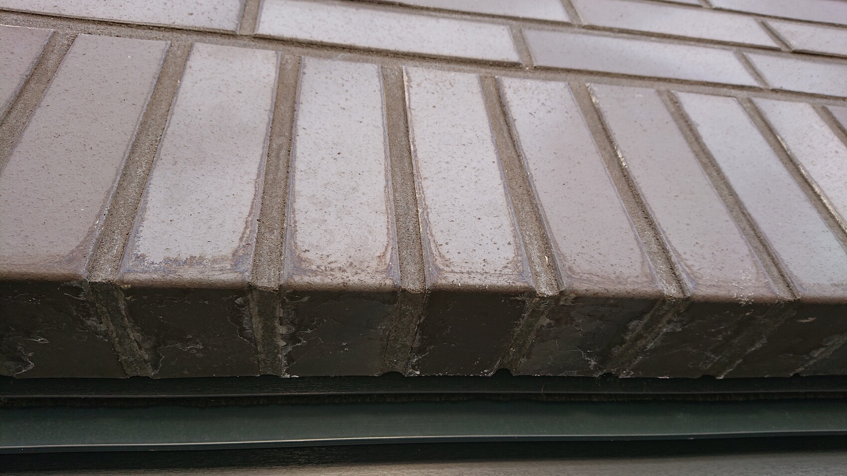 Nahaufnahme grauer Beton-Dachziegel an einer Dachkante.