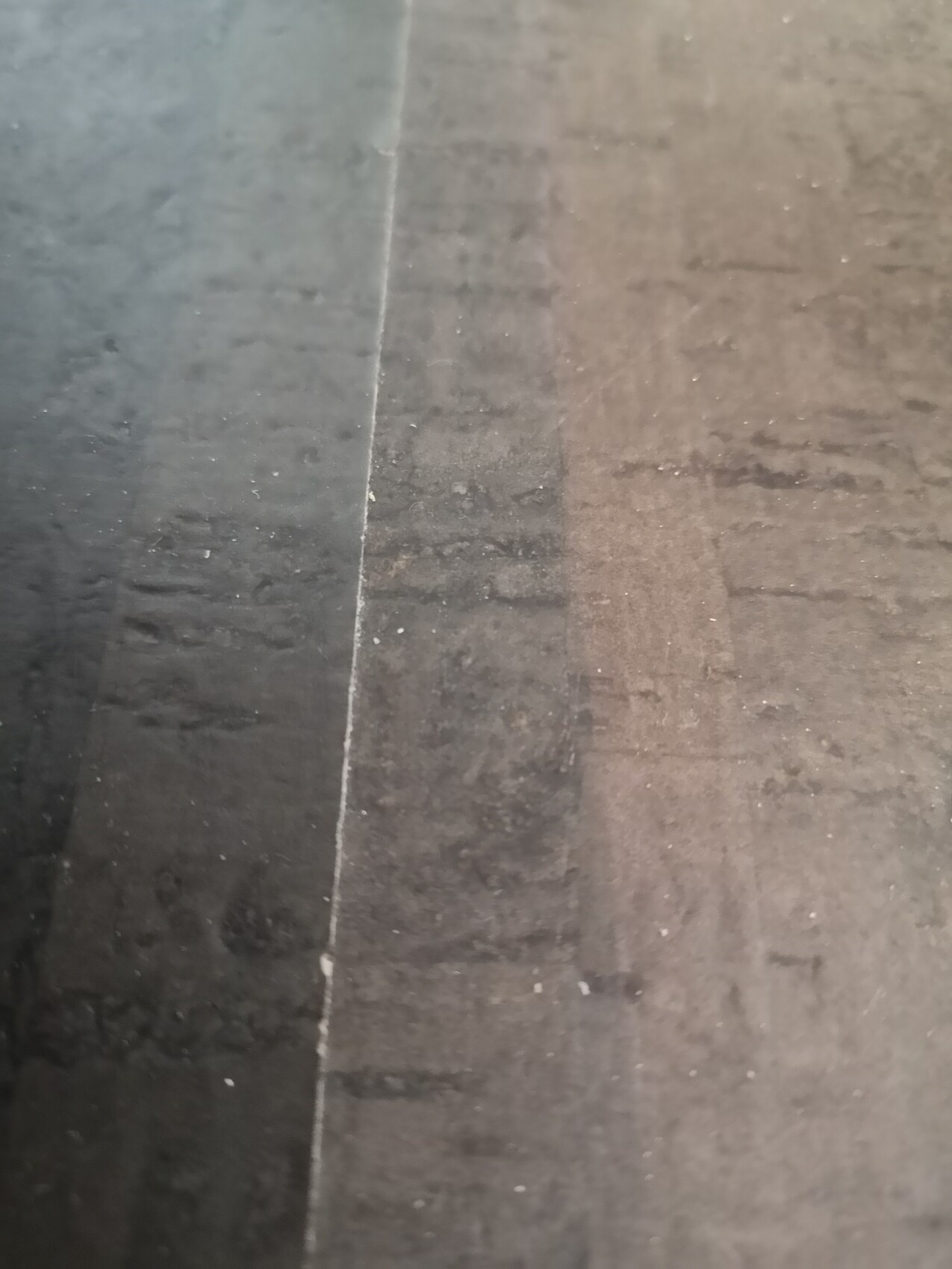 Nahaufnahme einer Holzboden-Oberfläche: zwei Platten, linke dunkel, rechte hell, sichtbare Naht