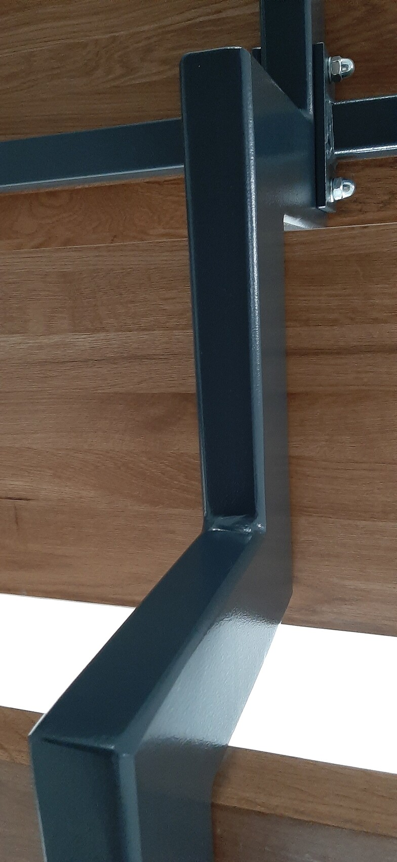 Blauer Metallrahmen eines Möbelgestells mit Holzplatte und Schraubverbindungen.