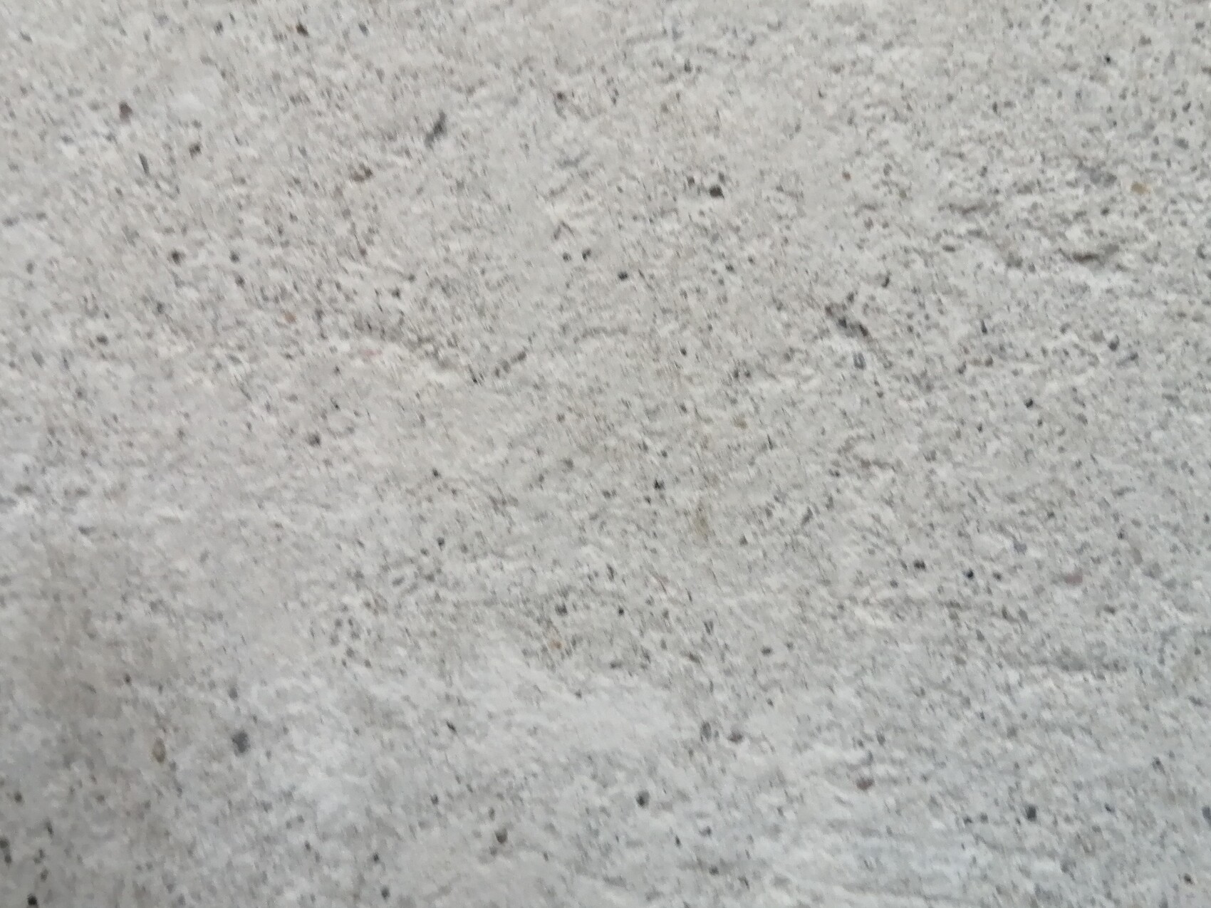 Nahaufnahme einer rauen grauen Betonoberfläche mit kleinen Kieselchen