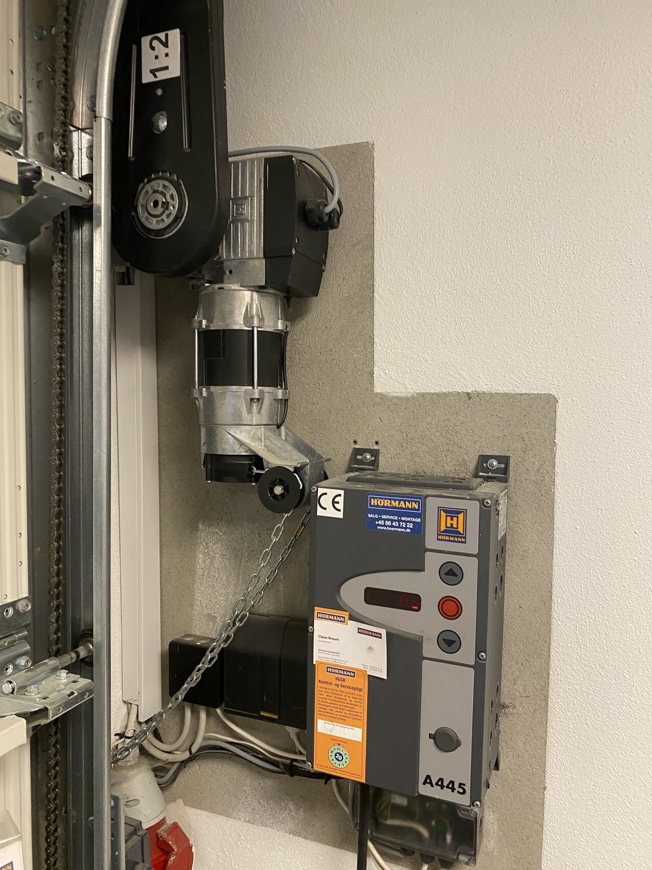 Elektrischer Garagentorantrieb mit Motor, Steuergerät und Verkabelung an der Wand
