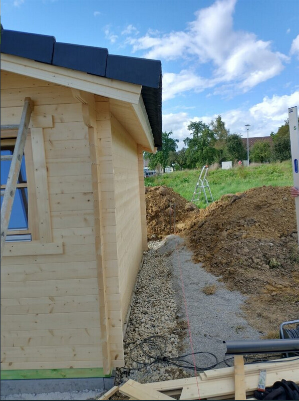 Holzhaus-Rohbau auf Bauplatz mit Holzwänden, Baugeräten und Materialien