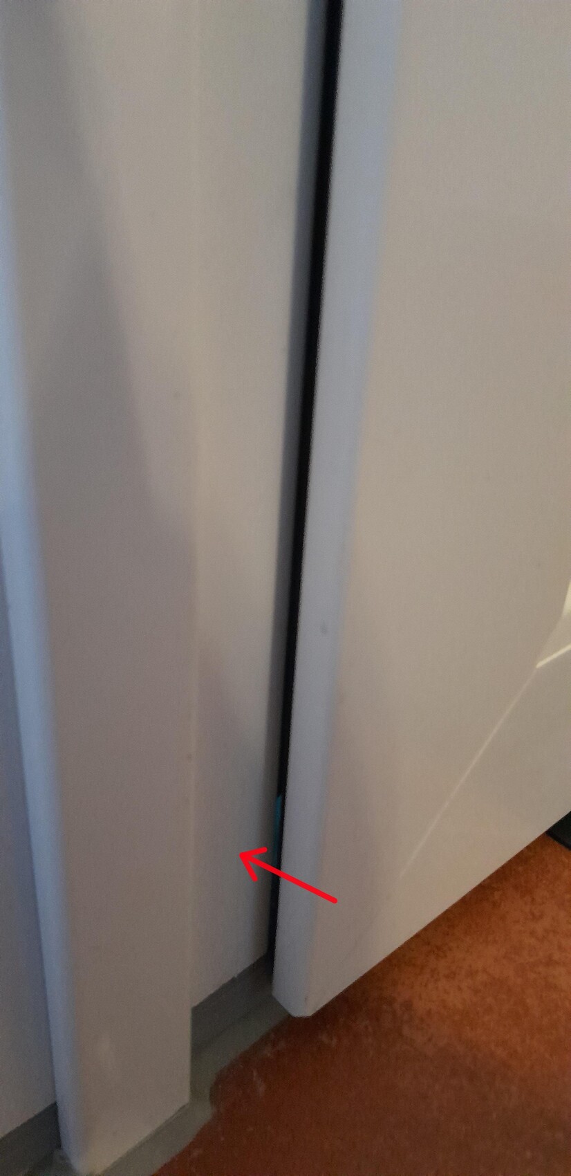Spalt zwischen zwei Türen; am unteren Rand steckt ein kleiner blauer Gegenstand.