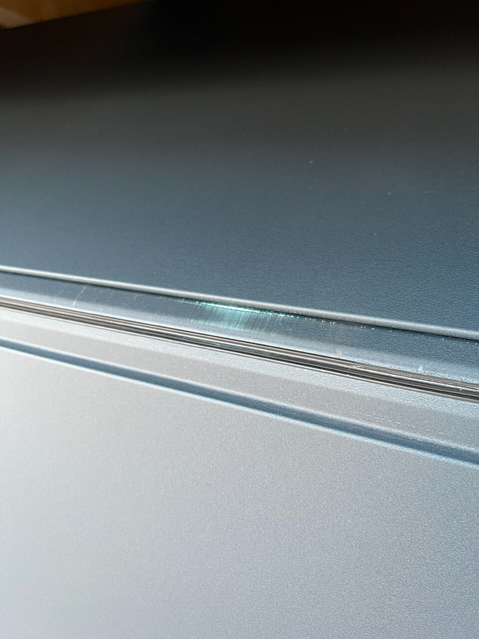 Nahaufnahme der Autotürkante aus silbernem Metall mit leichter Kratzspur an der Dichtung