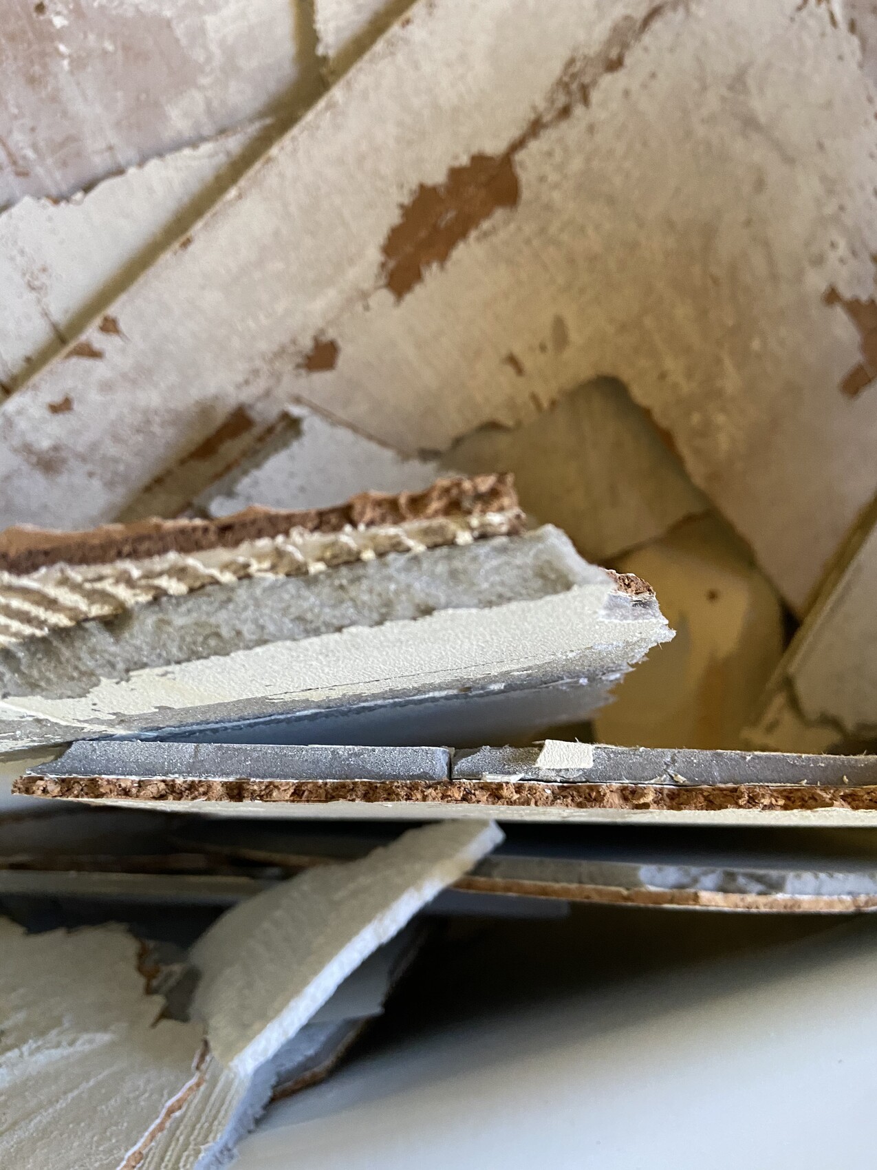 Zerbrochene Gipskarton- oder Trockenbauplatten vor beschädigter Wand mit Rostspuren.