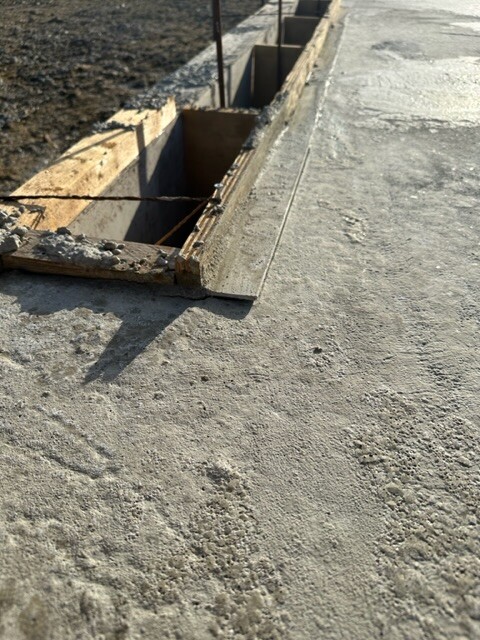 Rechteckige Bauöffnung in einer Betonplatte, Holzformrahmen und Bewehrung sichtbar.