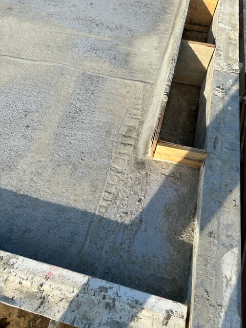 Betonboden mit Holzschalung, Baugrube und Schalungsbrettern.