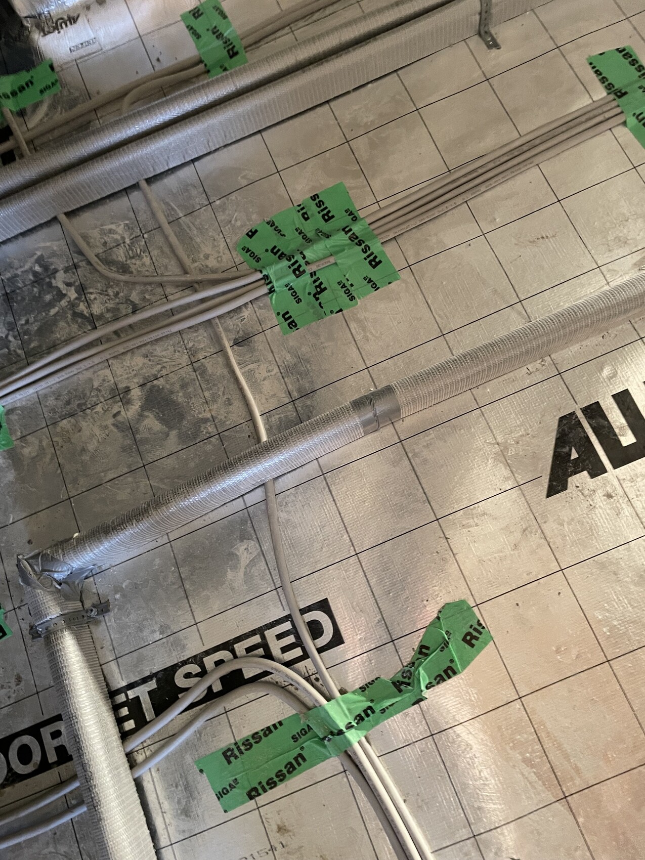 Isolierte Metall-Lüftungsrohre und Kabel liegen auf einer Baustelle.