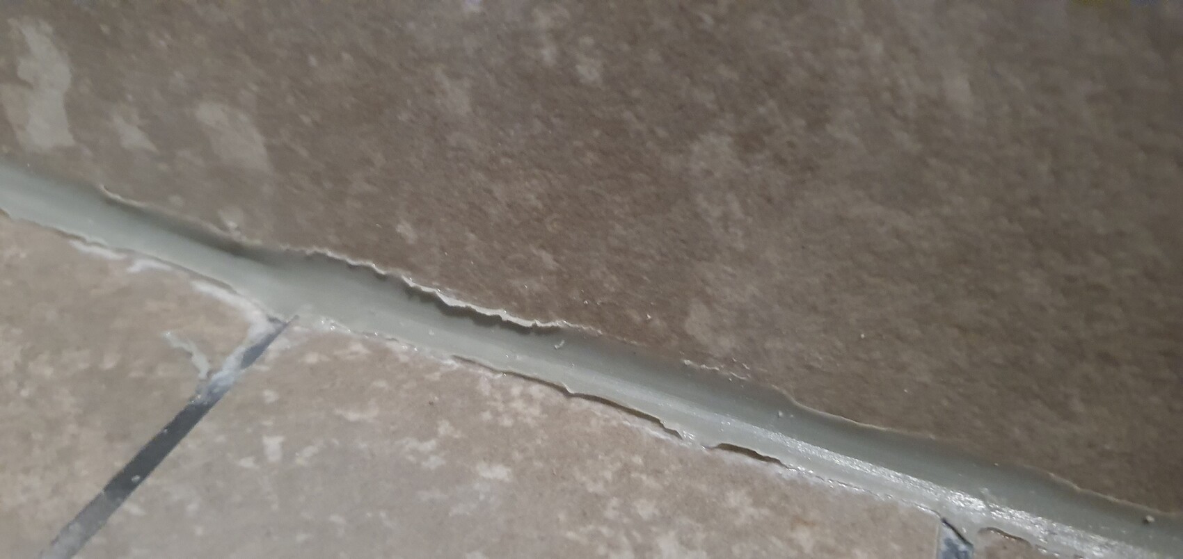 Nahaufnahme brauner Fliesen mit rissiger grauer Fuge