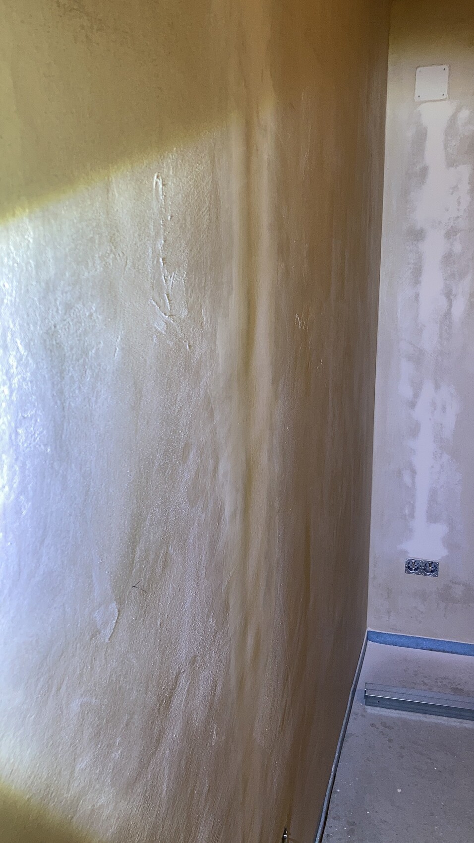 Renovierter Innenraum mit ungleichmäßig verputzten Wänden, Boden mit Abdeckband