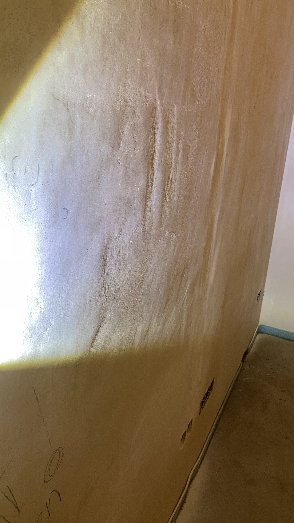 Beige, gewölbte Innenwand mit rauer Textur, Bodenleiste und mehreren kleinen Öffnungen unten.