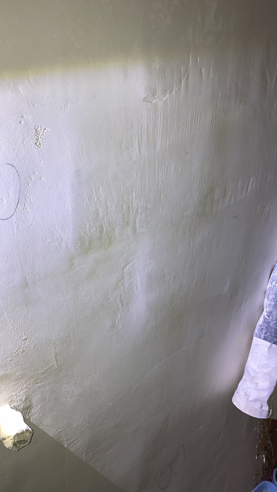 Rauputzwand mit rauer Struktur; Kreidezeichnung links, rechter Arm in Weiß.