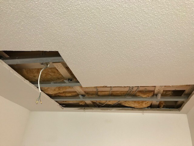 Decke mit Loch: freigelegte Dämmung, Metallträger und Kabel sichtbar