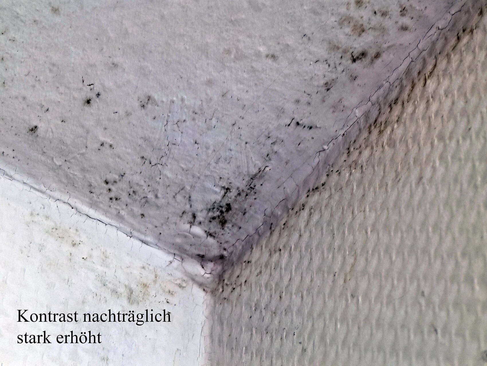 Weiße Wandenecke mit Rissen und schwarzen Flecken; Kontrast stark erhöht.