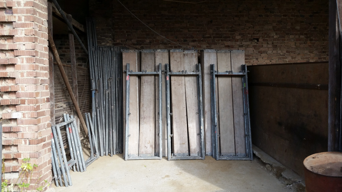 Lagerraum mit schweren Holz- und Metalltüren, gegen Backsteinwand gelehnt.