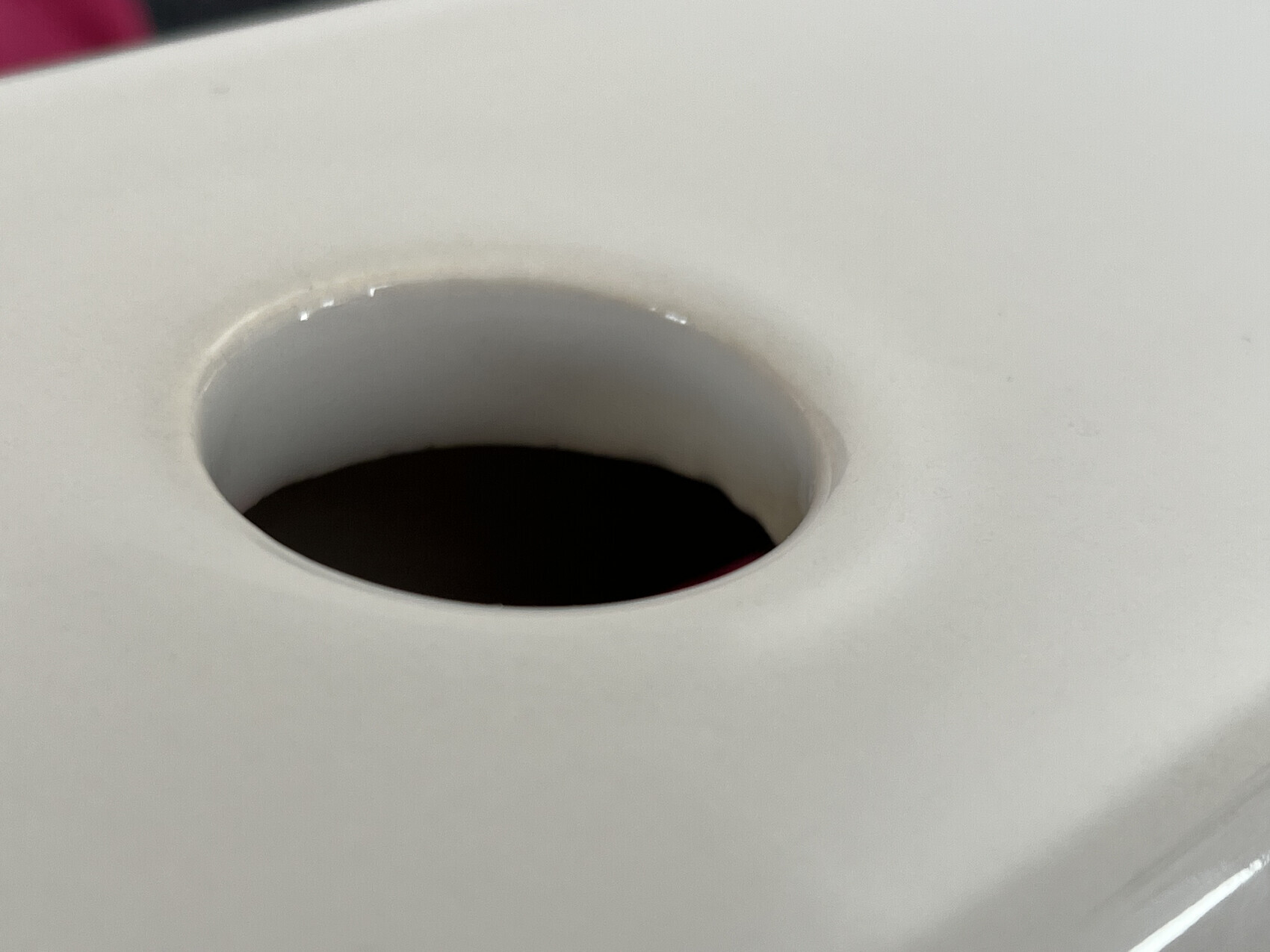 Nahaufnahme eines runden Lochs in einer weißen Oberfläche mit dunklem Innenraum.