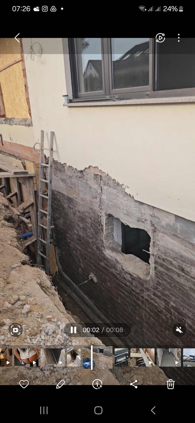 Außenwand-Baustelle: freigelegtes Kellerfundament, Loch in der Wand, Leiter lehnt an der Wand.
