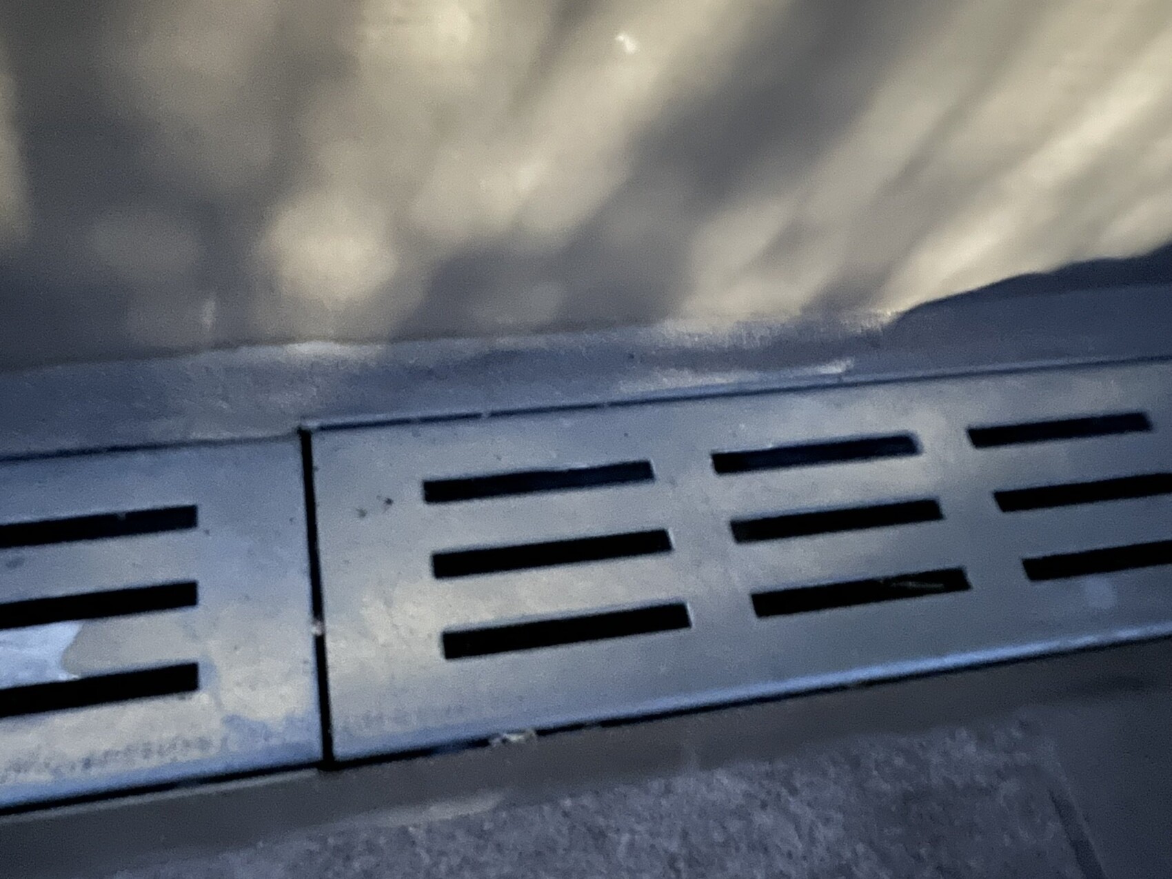 Nahaufnahme eines horizontalen Lüftungsgitters aus Metall mit rechteckigen Schlitzen