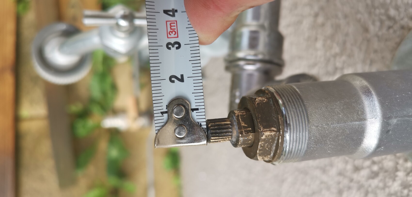 Maßband neben einer Metallrohrverbindung mit Gewinde; Messung ca. 3 cm.