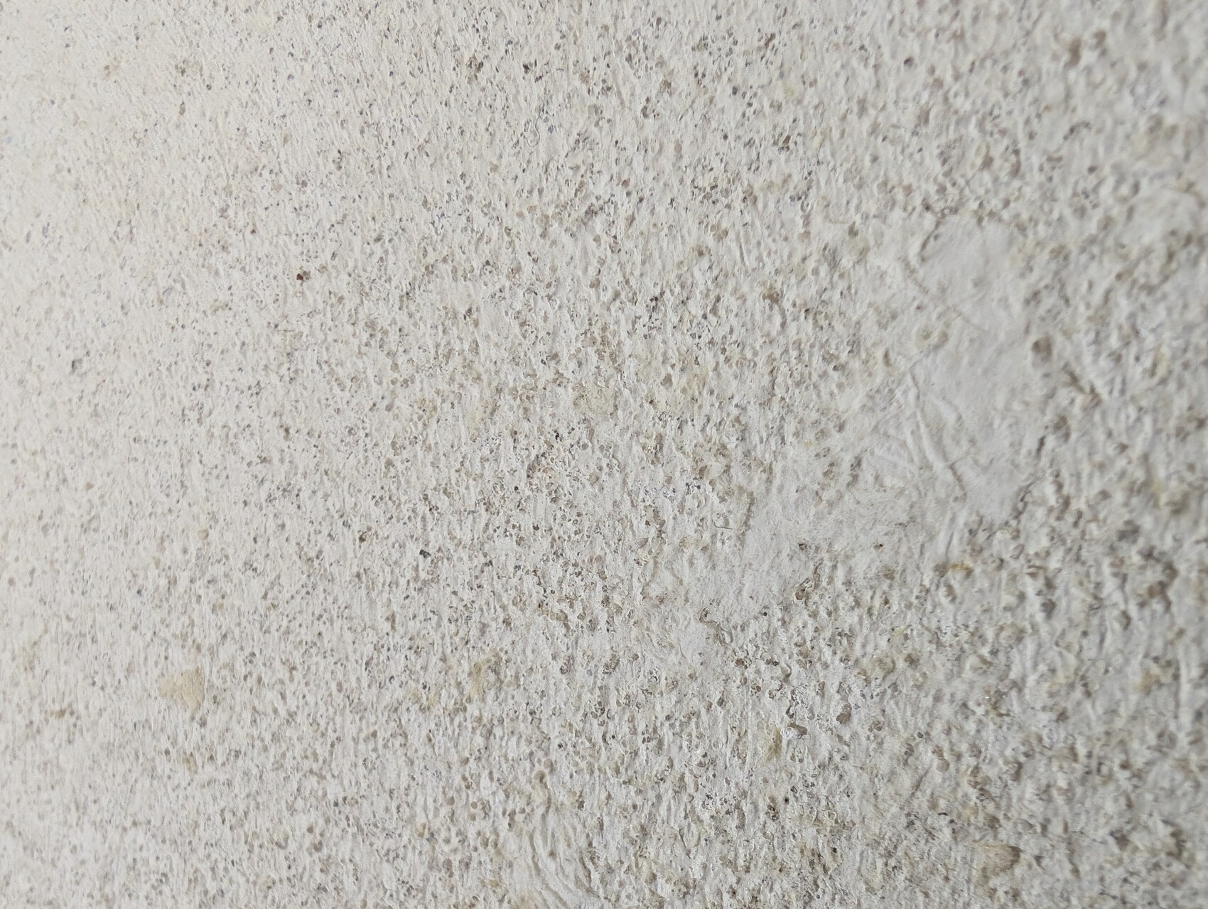 Nahaufnahme einer grob texturierten Steinwand mit unregelmäßiger Oberfläche.