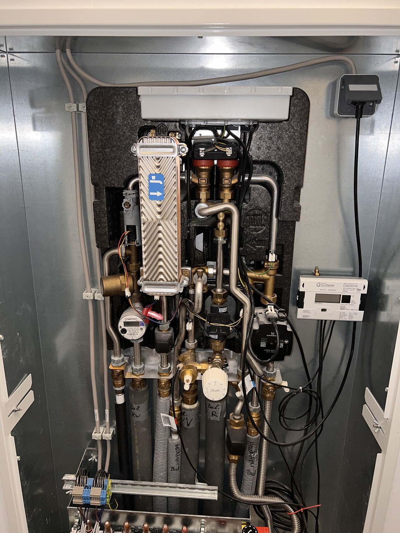 Blick auf eine Heizungsanlage: Rohre, Pumpe, Ventile, Zähler und Steuergerät.