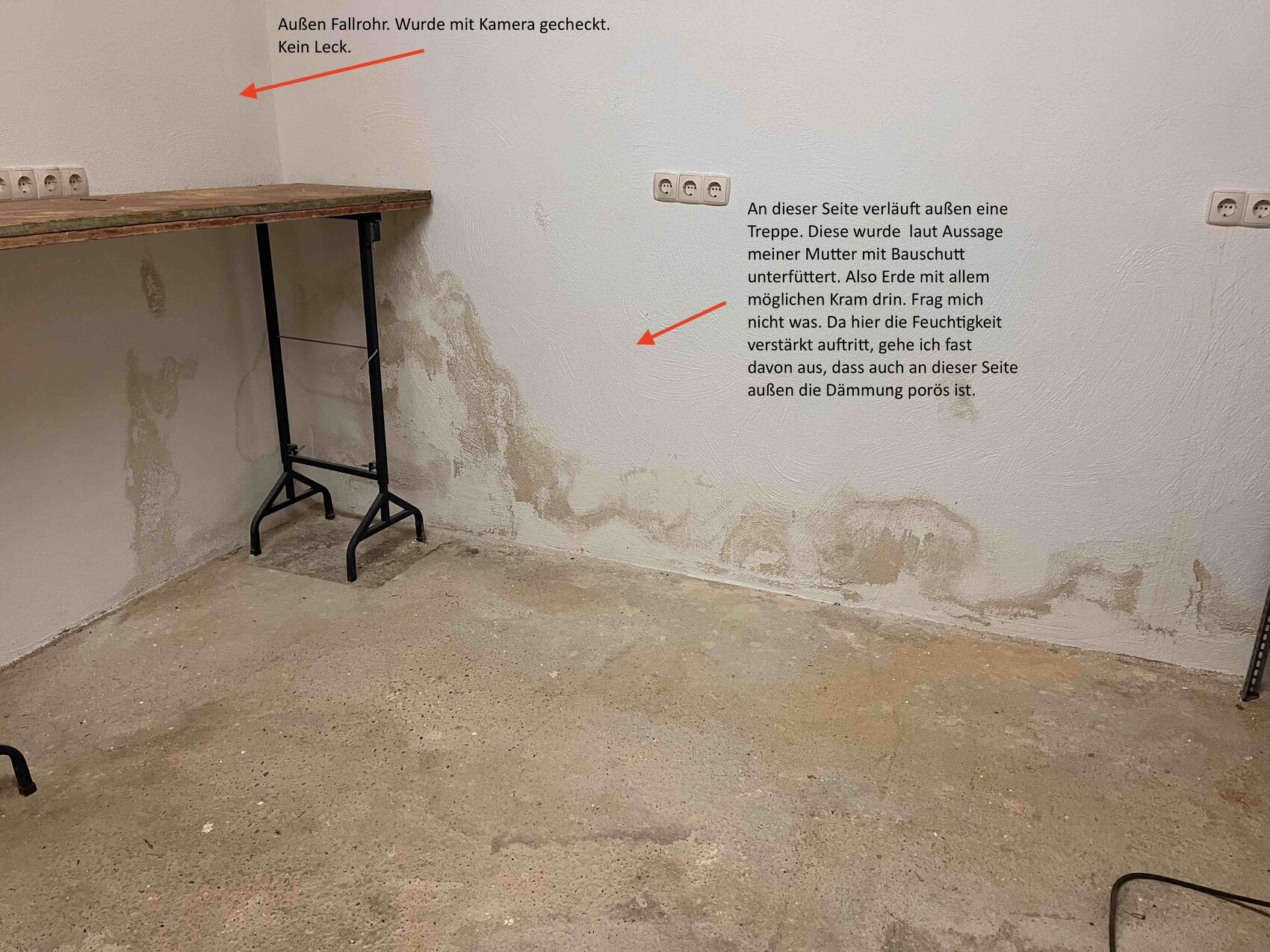 Ecke eines Kellerraums mit feuchter Wand, Holzwerkbank links und Steckdosen.