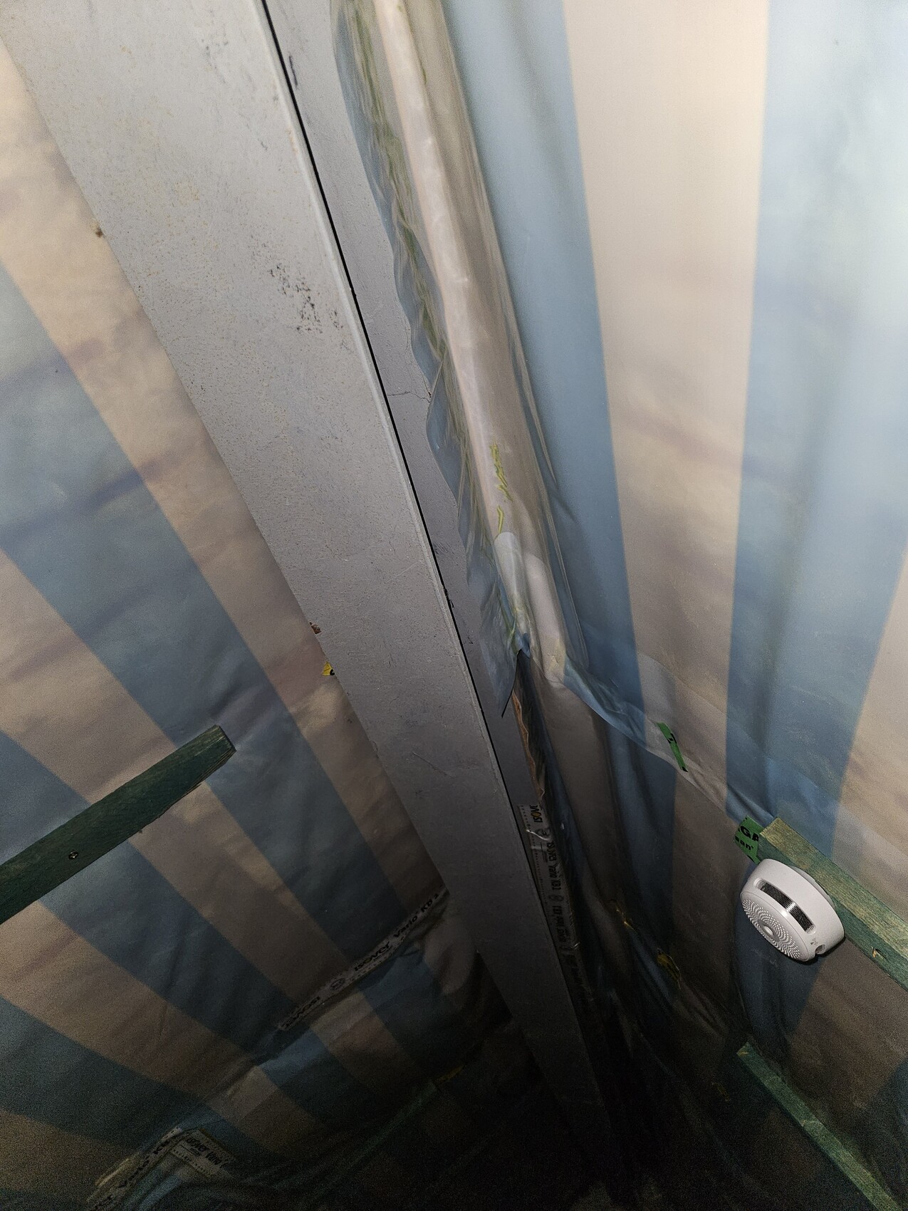 Enger Renovierungsbereich: Metallrahmen, blau-weiße Abdeckfolie, Kabel und Rauchmelder.