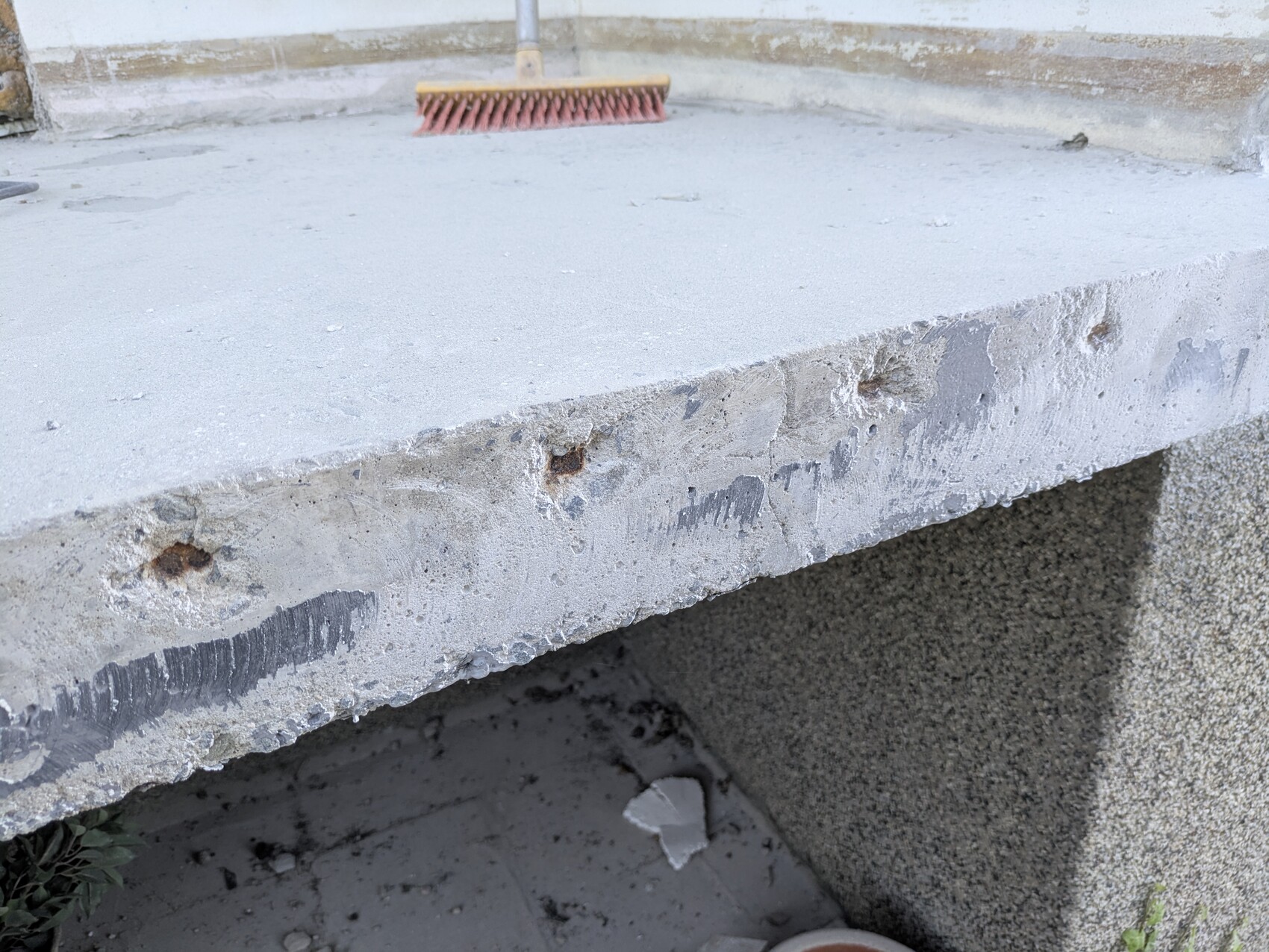 Außenbetonplatte mit rauer Kante; roter Besen liegt darauf.