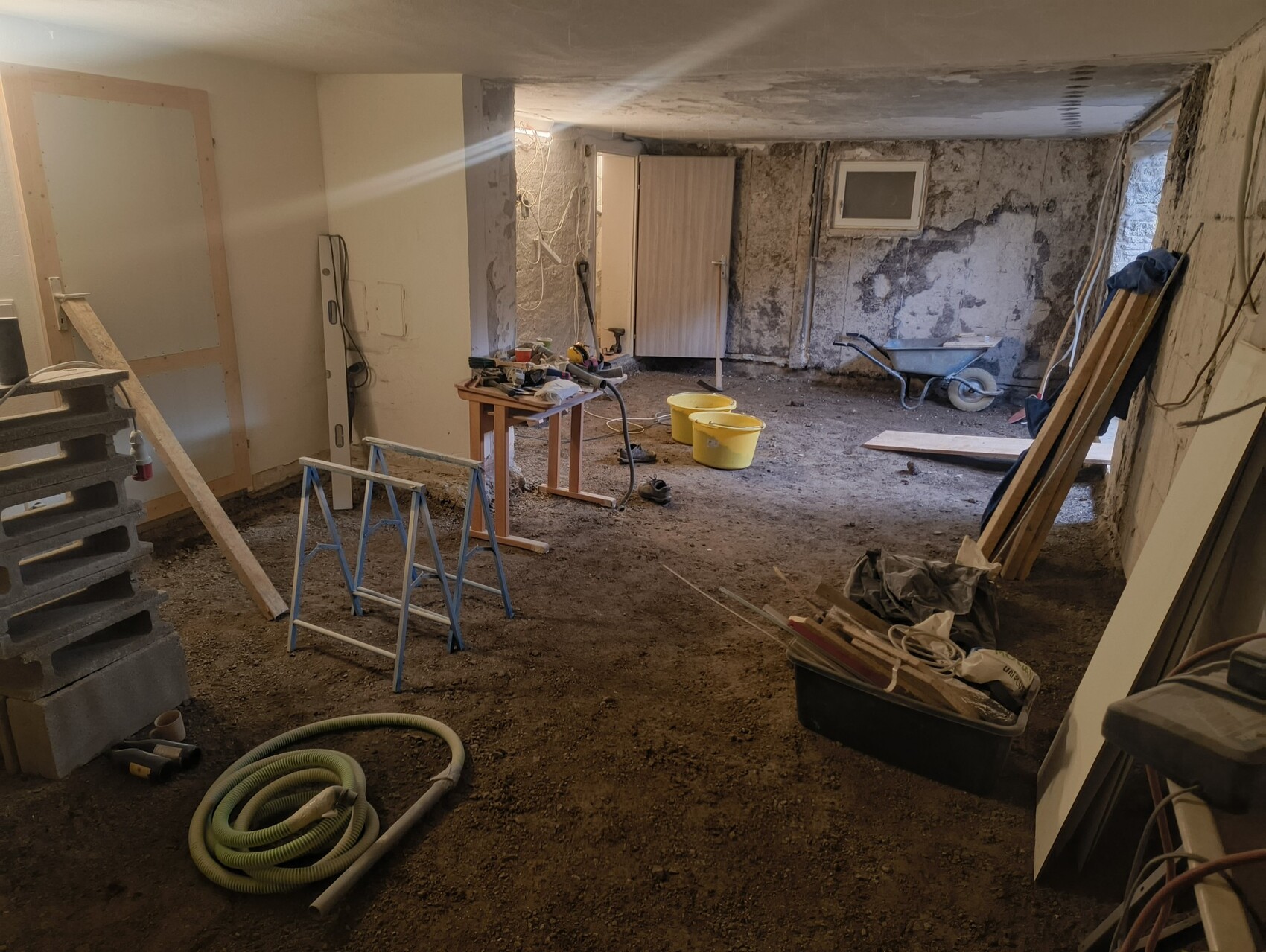 Keller-Bauplatz im Innenausbau: Erde Boden, Werkzeuge, Schubkarren und Bauholz.