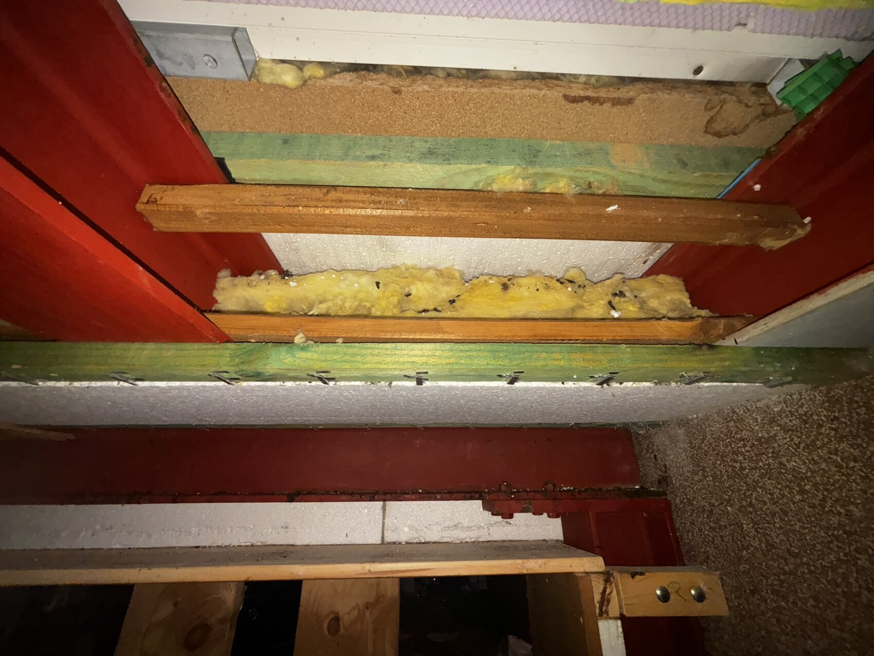 Wandaufbau mit Dämmmaterial zwischen Holzlatten und rotem Stahlträger