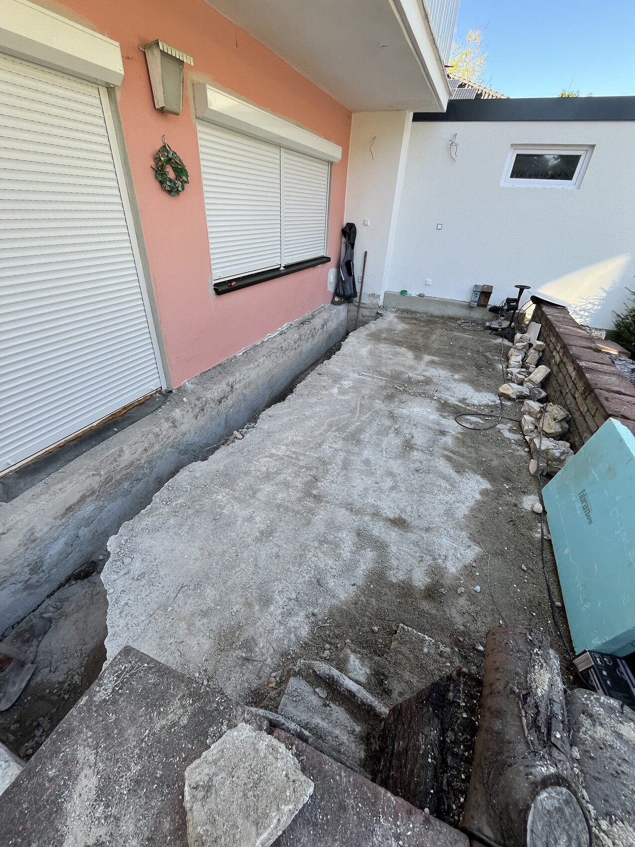 Außenbereich eines Hauses mit unfertiger Bodenplatte, Stufen und Baumaterialien