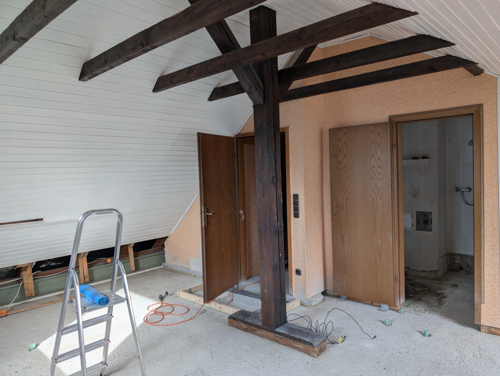 Innenraum während Renovierung mit dunklen Holzbalken, Leiter und Bauwerkzeugen