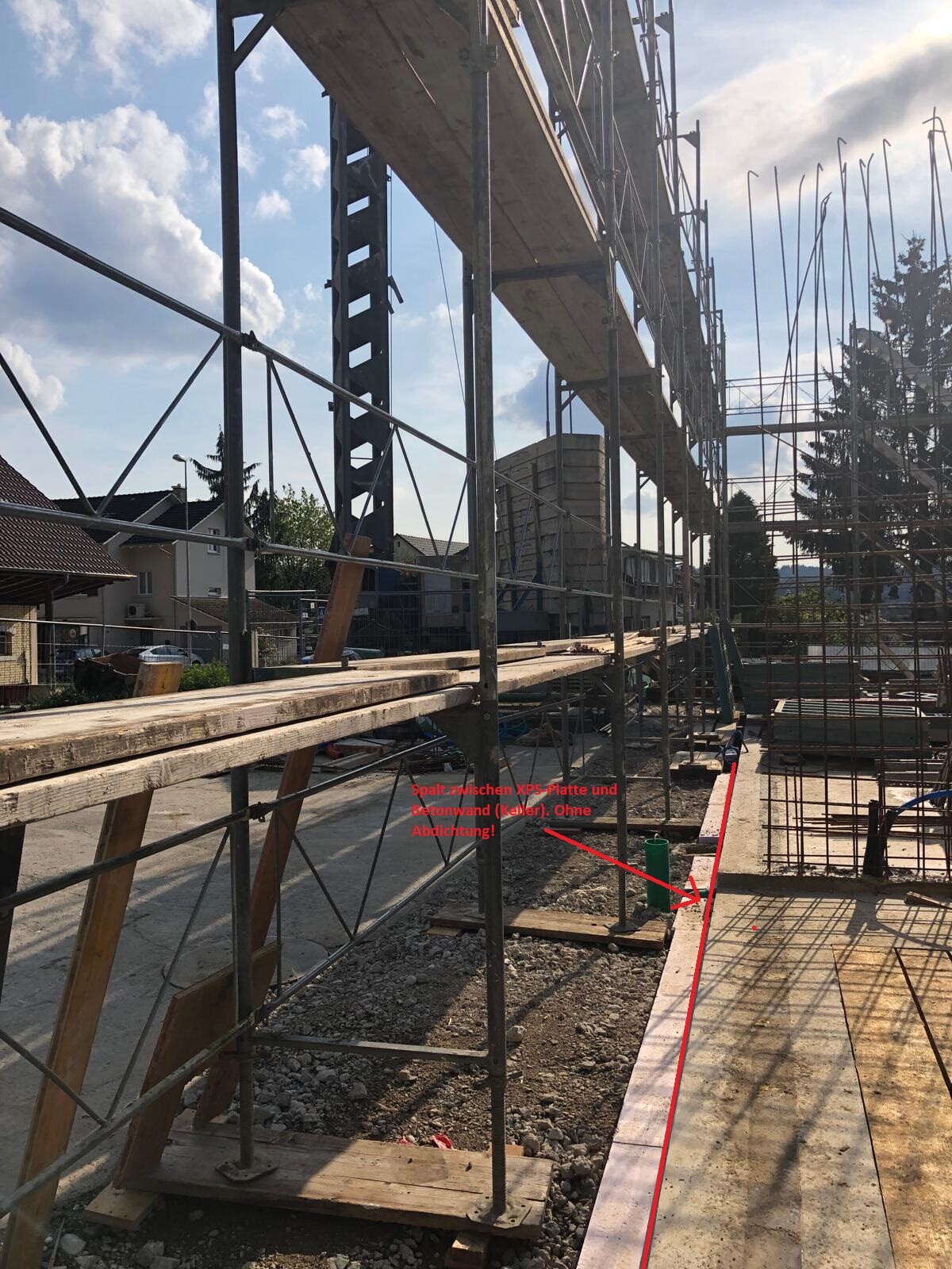 Baustelle mit Stahlgeruest, Holzplanken und Fundamentarbeiten am Neubau