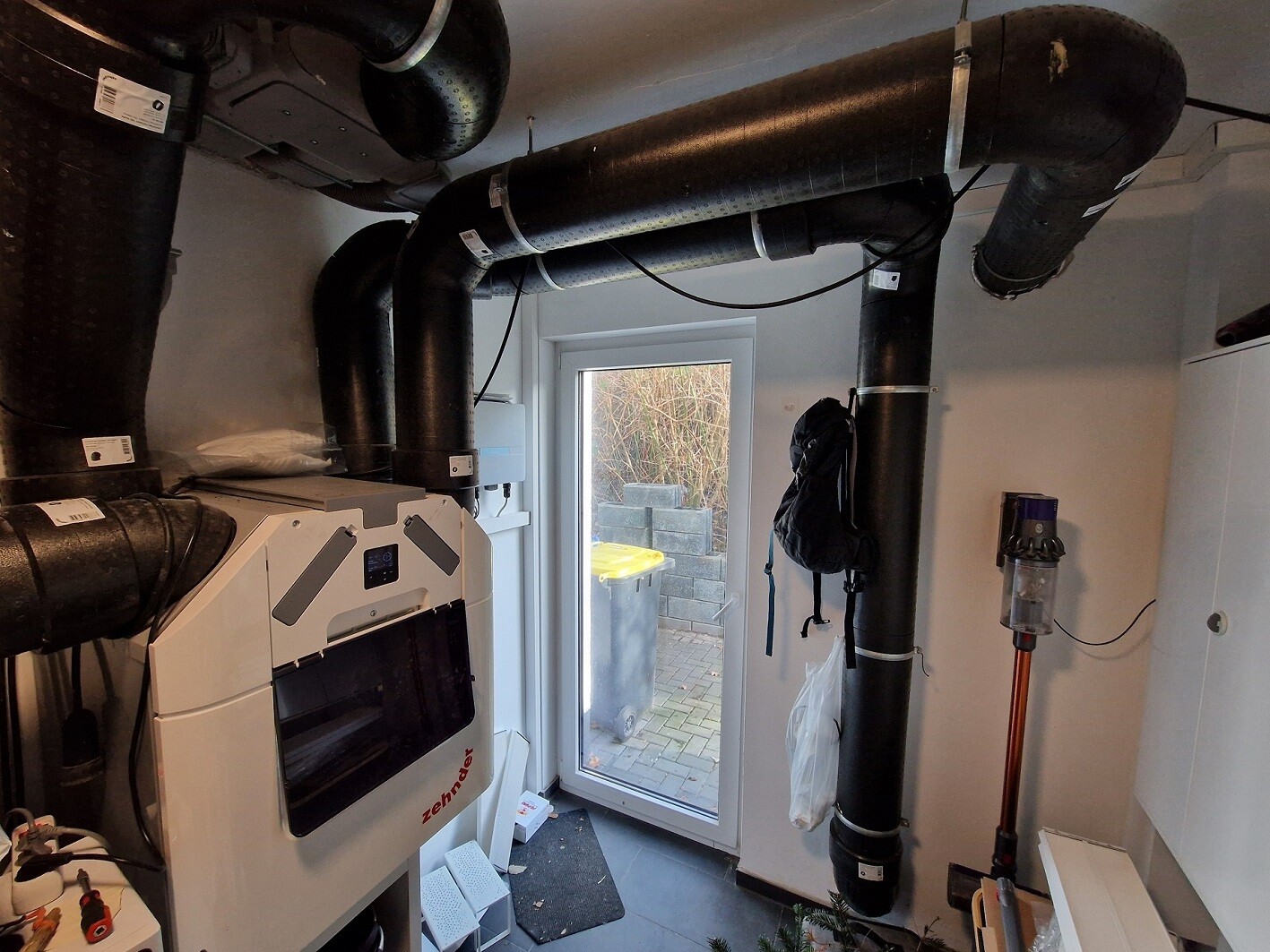 Kellerraum mit Heizungsanlage, großen schwarzen Rohrleitungen und Lüftungssystemen.