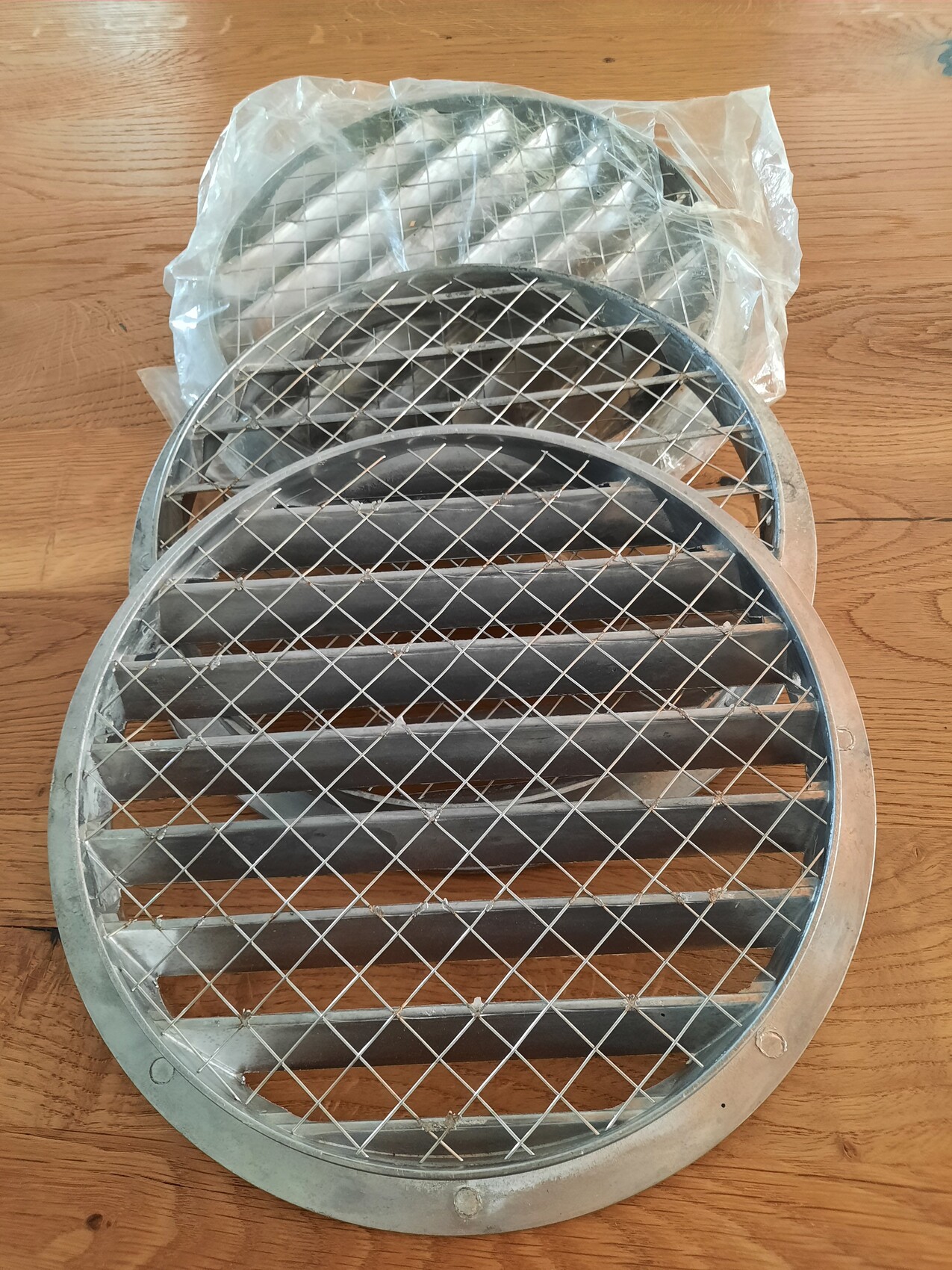 Rundes Metall-Lüftungsgitter mit Drahtnetz auf Holzoberfläche