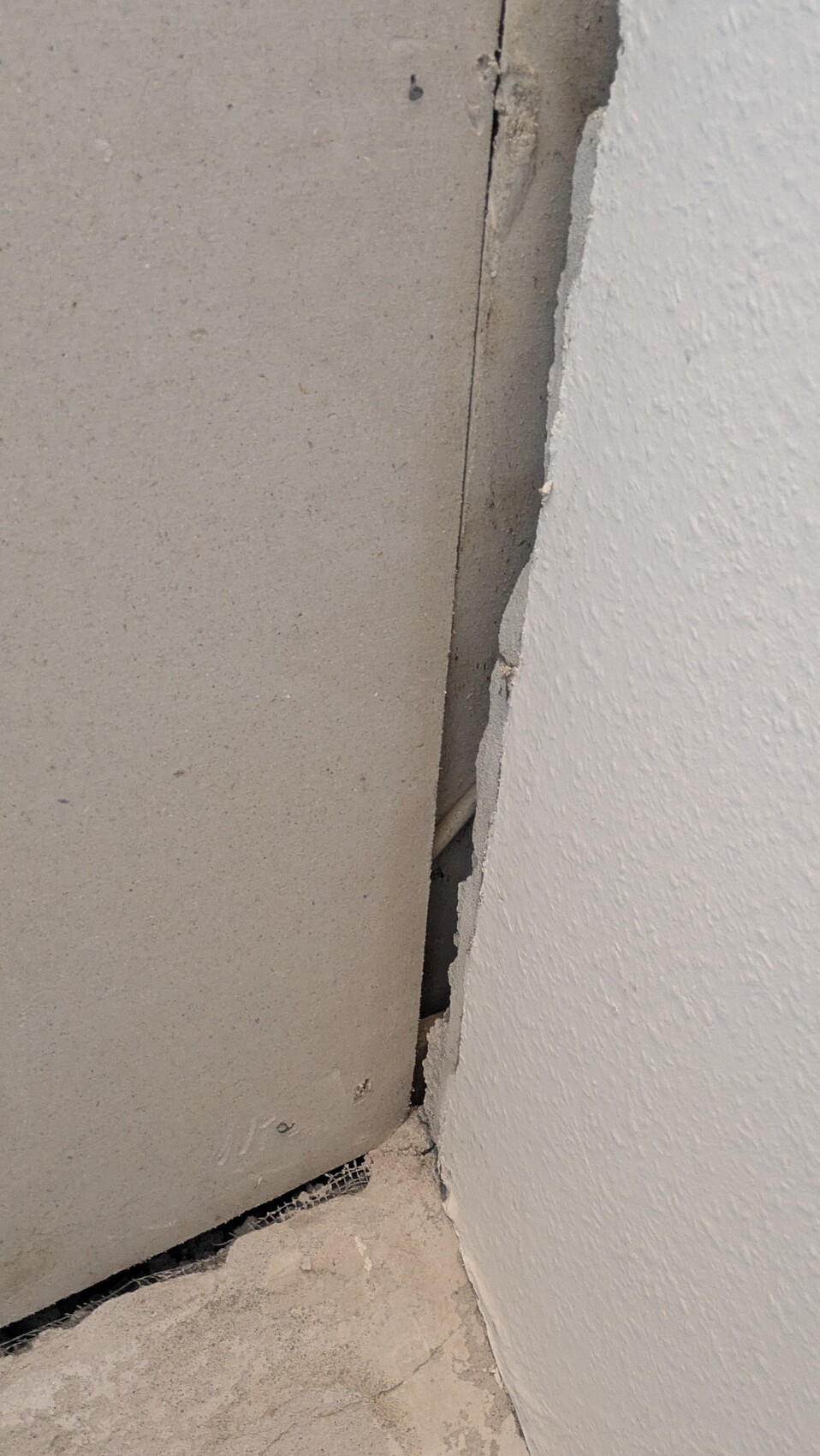 Nahaufnahme eines Spalts zwischen Wand und Boden mit Putz- und Betonbruch