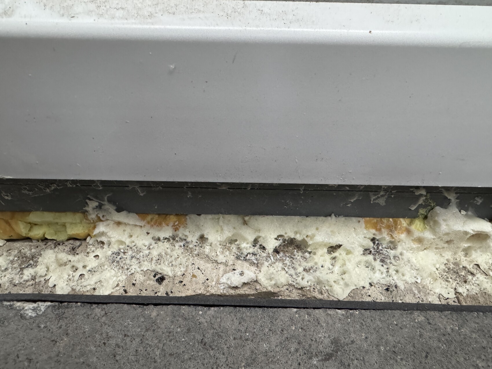 Nahaufnahme einer Gebäudefassade mit sichtbarer Dämmung aus Schaum zwischen Wand und Fundament.