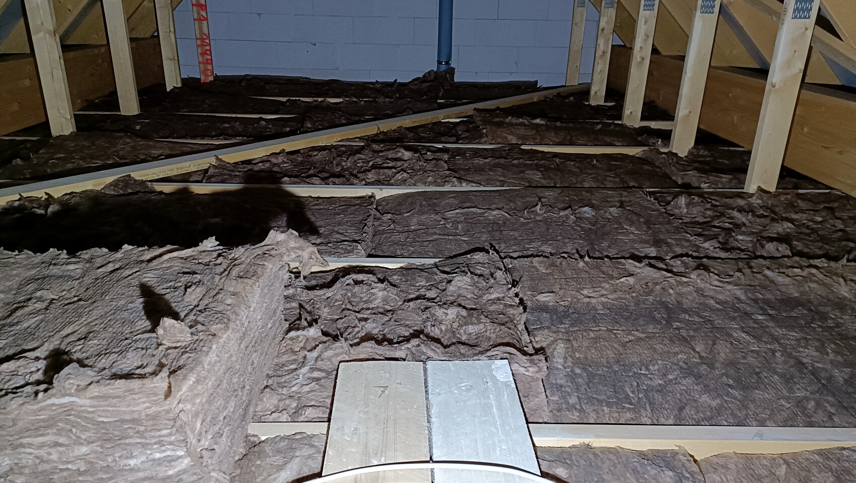 Unverkleideter Dachboden-Rohbau mit Holzständern und dunkler Mineralwolle-Dämmung